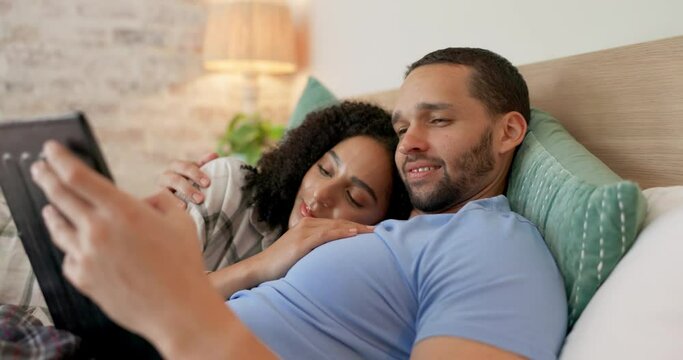 Couple, tablet and relax on bed, home and morning with video, movie and kiss with love, care and hug. Man, woman and digital touchscreen with typing, social network app and bonding together in house