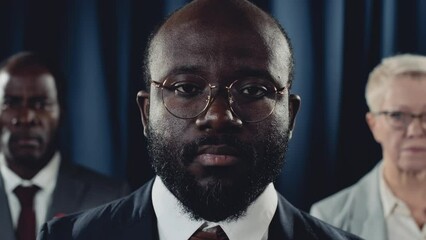 Close-up portrait shot of charismatic confident young African American male president, black vice president and Caucasian female press secretary posing in front of USA flag and looking at camera