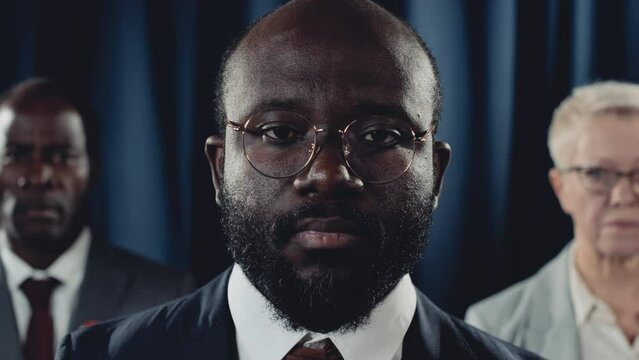 Close-up portrait shot of charismatic confident young African American male president, black vice president and Caucasian female press secretary posing in front of USA flag and looking at camera