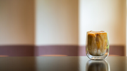 Iced coffee in a glass on the table with blurred background.