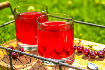 Fresh cherry juice on a wooden tray outdoor. Cherry compote