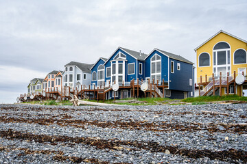 Colorful seaside lodging with satellite antennas, rocky beach at low tide
