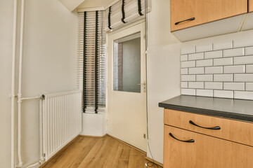 an empty room with wood flooring and white tiles on the walls, there is a small window in the corner
