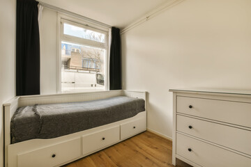 a bedroom with a bed, dresser and window in the corner of the room is very light wood flooring