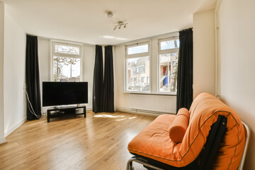 a living room with wood flooring and white walls, including a large flat screen tv set on the wall