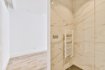 a modern bathroom with marble walls and floor to the right, there is a white towel rack on the wall