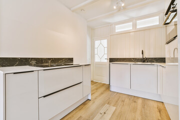 a kitchen with white cabinets and marble counter tops on the island in front of the sink is black and white