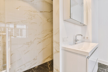 a bathroom with marble walls and white fixtures on the wall behind it is a sink, mirror and shower stall