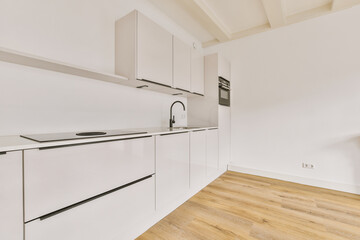 a kitchen with white cupboards and wood flooring in the middle part of the room, there is an oven...