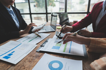 Businesswoman teamwork discussing brainstorming and calculating with calculator on evaluation data in conference room Focus on business growth and point out financial accounting charts.