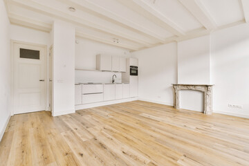 an empty living room with wood flooring and white cupboards on either side of the door to the kitchen
