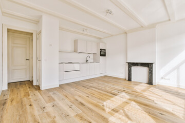 an empty living room with wood flooring and white cupboards on either side of the door to the kitchen