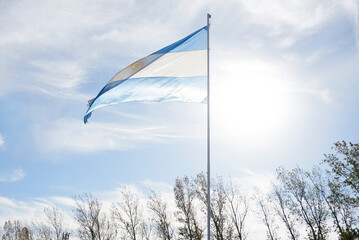 Argentine flag waving on a flagpole outdoors, in a rural environment. Patriotic symbol of Argentina.
