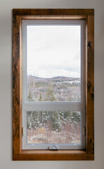 vue au travers d'une fenêtre avec un cadre en bois sur une forêt au bas à partir de l'intérieur d'une maison lors d'une journée ennuagée