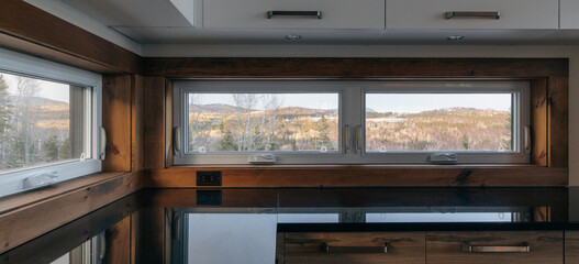 vue sur un comptoir de cuisine noir avec vue vers l'extérieur à travers des fenêtres...