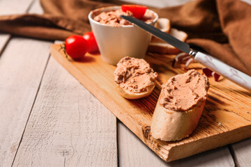 Board of sandwiches with tasty pate on light wooden table, closeup