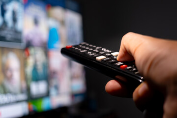 His hand was holding a remote control. Multimedia TV broadcasting online for entertainment to watch...