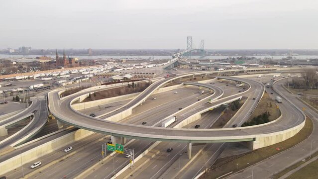 Winding road and Ambassador bridge connecting USA and Canada with traffic of semi trucks, aerial view