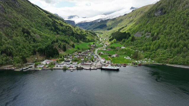 Beautiful town of Eidsdal More and Romsdal with mountain valley behind and ferry alongside pier - Springtime aerial with lush green hillsides and snow capped mountains - Norway