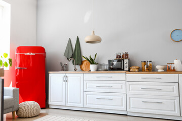 Interior of light kitchen with red fridge, counters and pouf