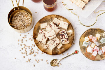 Plates with pieces of tasty marble halva and turkish delight on light background
