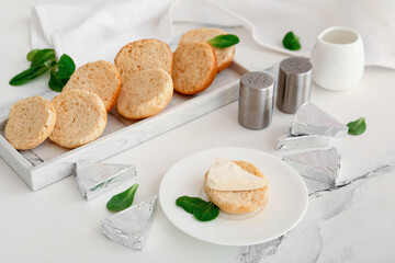 Plates with croutons and triangles of tasty processed cheese on white marble background