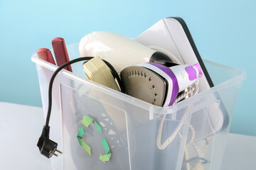 Recycle bin with different household appliances on blue background