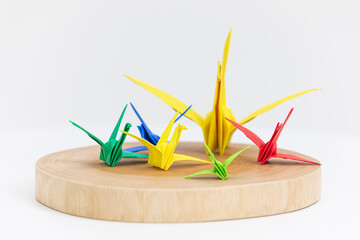 Colorful paper cranes placed on a wooden plate. 