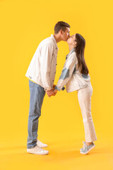 Happy young couple kissing on yellow background