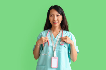 Female Asian medical intern with stethoscope on green background