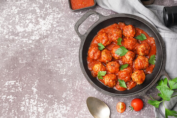 Frying pan of tasty meat balls with tomato sauce and parsley on grey background