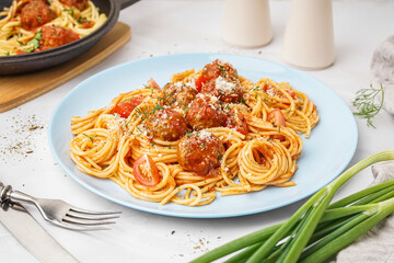 Plate of boiled pasta with tomato sauce and meat balls on white table