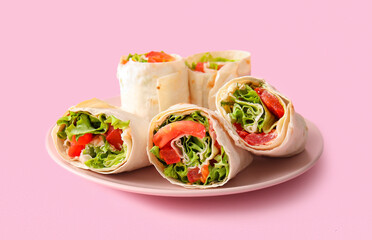 Plate of tasty lavash rolls with tomatoes and greens on pink background