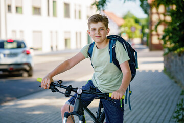 Handsome preteen boy going to school on bike. Teenager ride bicycle. Safe way to high school. Happy child boy with backpack on bike. Healthy outdoor activity for young student.