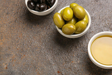 Bowls with ripe olives and oil on grunge background