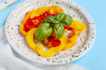 Plate with slices of tasty grilled bell pepper on blue background