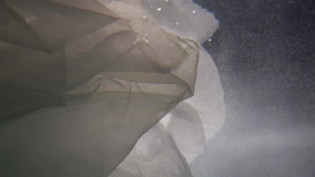 mysterious underwater shot, white fabric and tiny air bubbles floating in clear transparent water