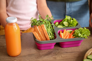 Little girl with school lunch box and her mother in kitchen, closeup