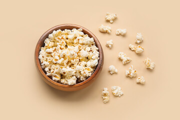 Fototapeta na wymiar Bowl with tasty popcorn on beige background