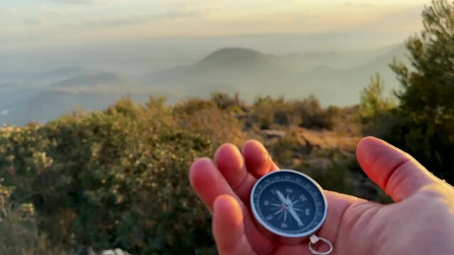 Compass in hand in mountains. Tourist compass for orientation on terrain. Magnetic declination сalculator. Map reading and land navigation concept. Orient on maps in mountains in Spain