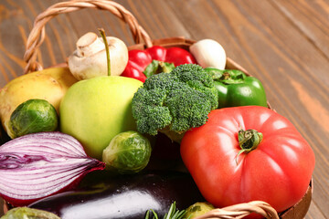 Wicker basket with fresh ripe vegetables on wooden background, closeup
