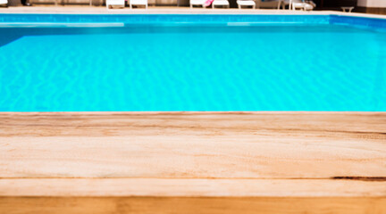 Image of wood table in front of swimming pool blur background. Brown wooden desk empty counter front view of the poolside on beautiful beach resort and outdoor spa.