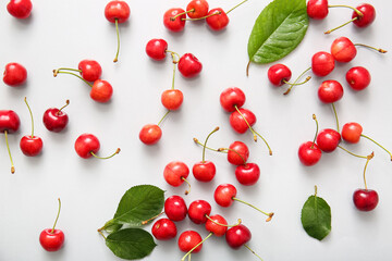 Many sweet cherries and leaves on white background