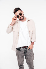 Portrait of handsome smiling stylish hipster lambersexual model. Sexy man dressed in white T-shirt and jeans. Fashion male isolated on white background in studio. In sunglasses