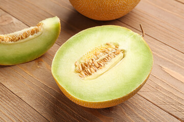 Half of sweet melon with piece on wooden background