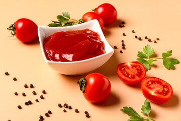 Bowl with tomato paste and fresh vegetables on orange background