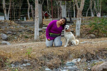 a female model sitting with a dog wearing purple jacket. Selective focus. Concept of friendship between human and animal.