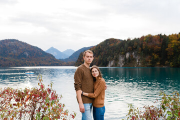 young couple of tourists embrace near an alpine lake