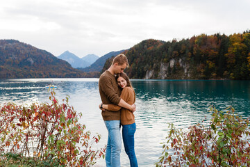 young couple of tourists embrace near an alpine lake