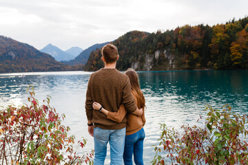 young couple of tourists embrace near an alpine lake